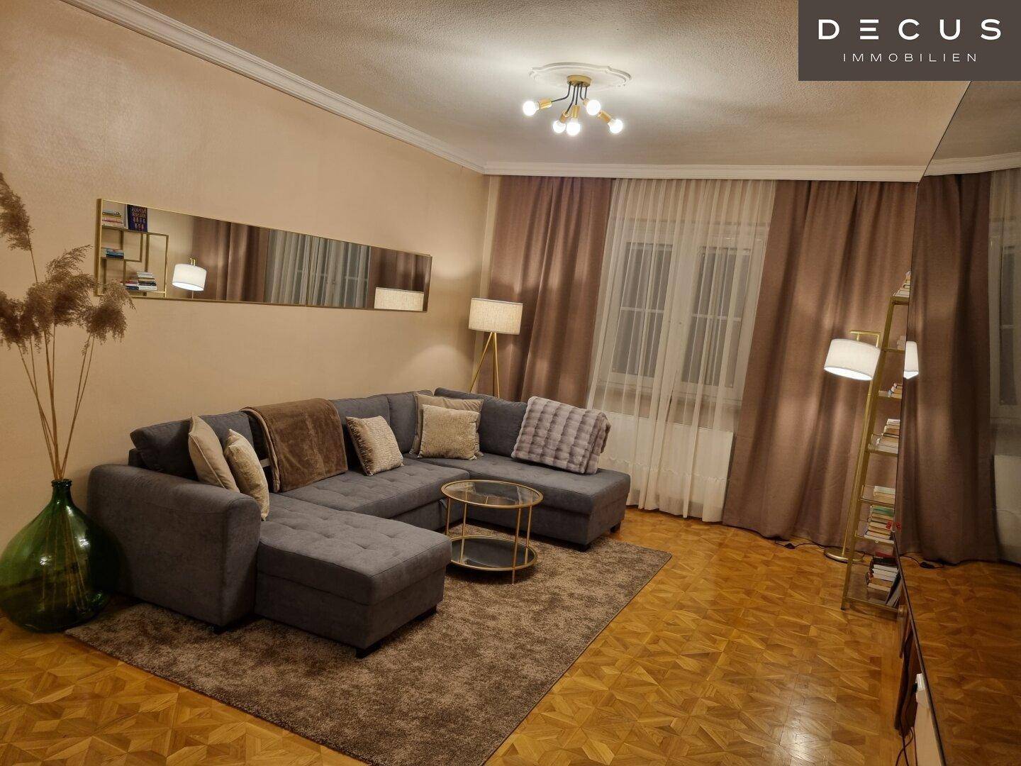 Gemütliches Wohnzimmer mit großem Ecksofa, Parkettboden und warmen Brauntönen.