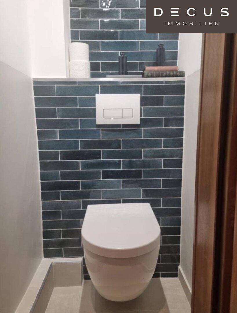 Modernes Gäste-WC mit Wand-WC und dunkelblauen Fliesen an der Wand.