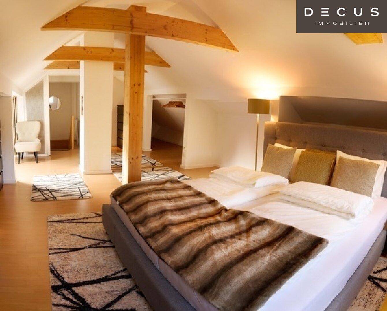 Geräumiges Schlafzimmer im Dachgeschoss mit Holzbalken und Parkettboden.