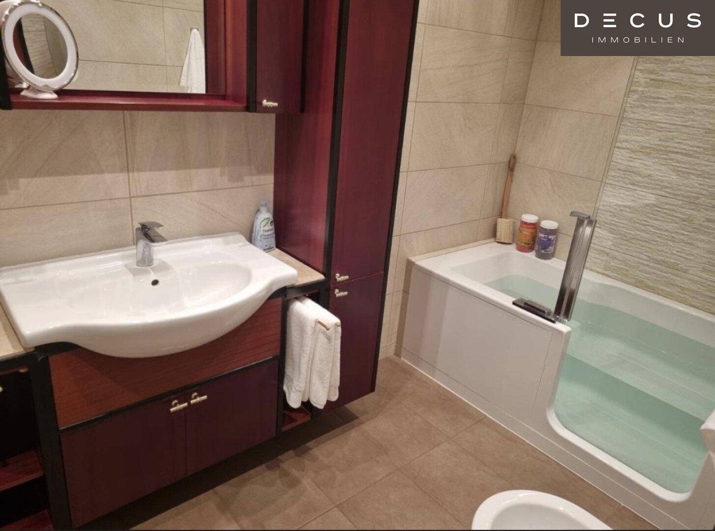 Badezimmer mit Badewanne, Einzelwaschbecken und dunklen Holzschränken.