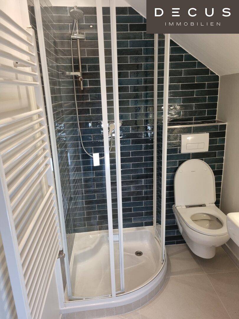 Modernes Badezimmer mit Duschkabine, Wand-WC und dunkelblauen Fliesen.