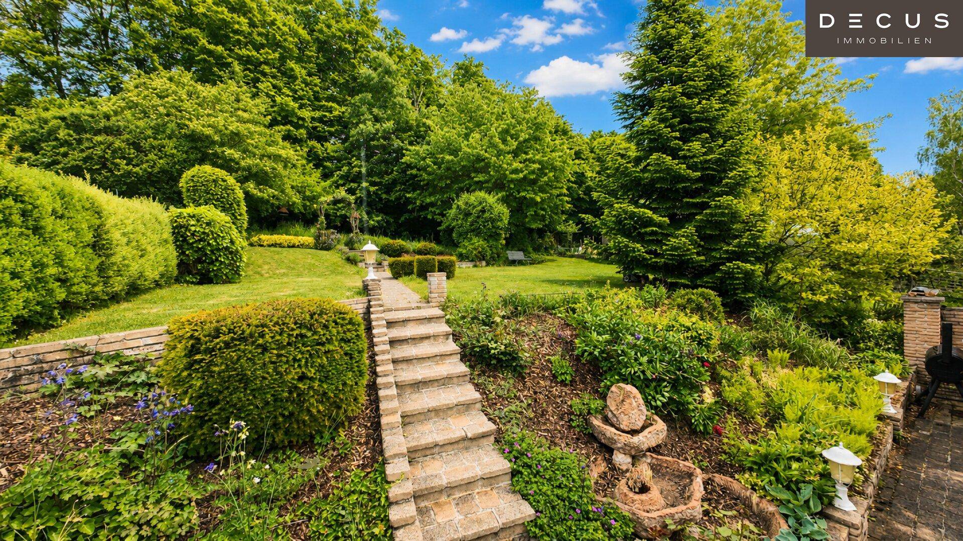 Terrassierter Garten mit Steinweg, Treppen und üppiger Bepflanzung.