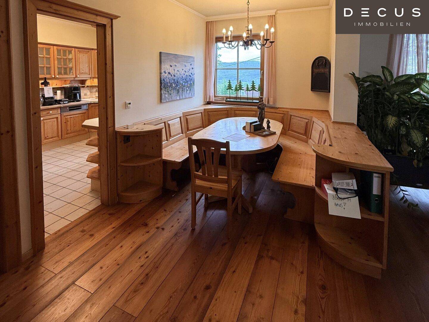 Rustikaler Essbereich mit Holzbänken, Esstisch und Zugang zur Küche.