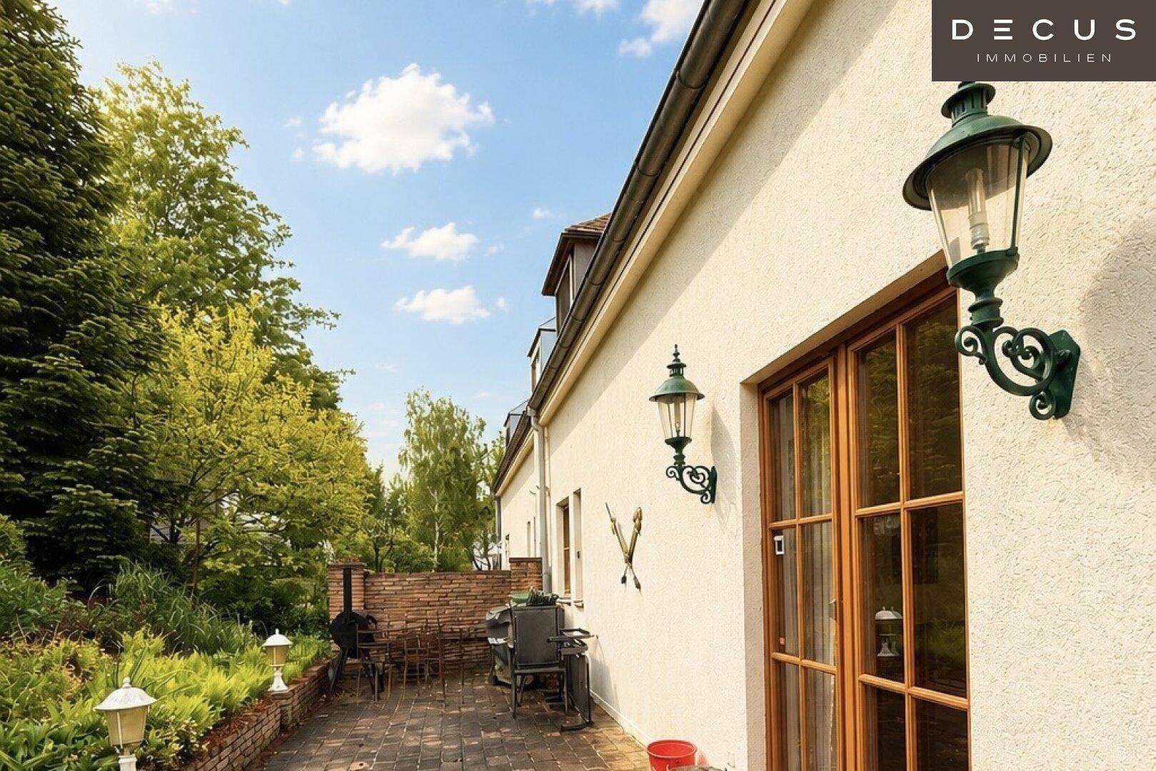 Gemütliche Terrasse mit Grillbereich, gepflastertem Boden und Laternenbeleuchtung.