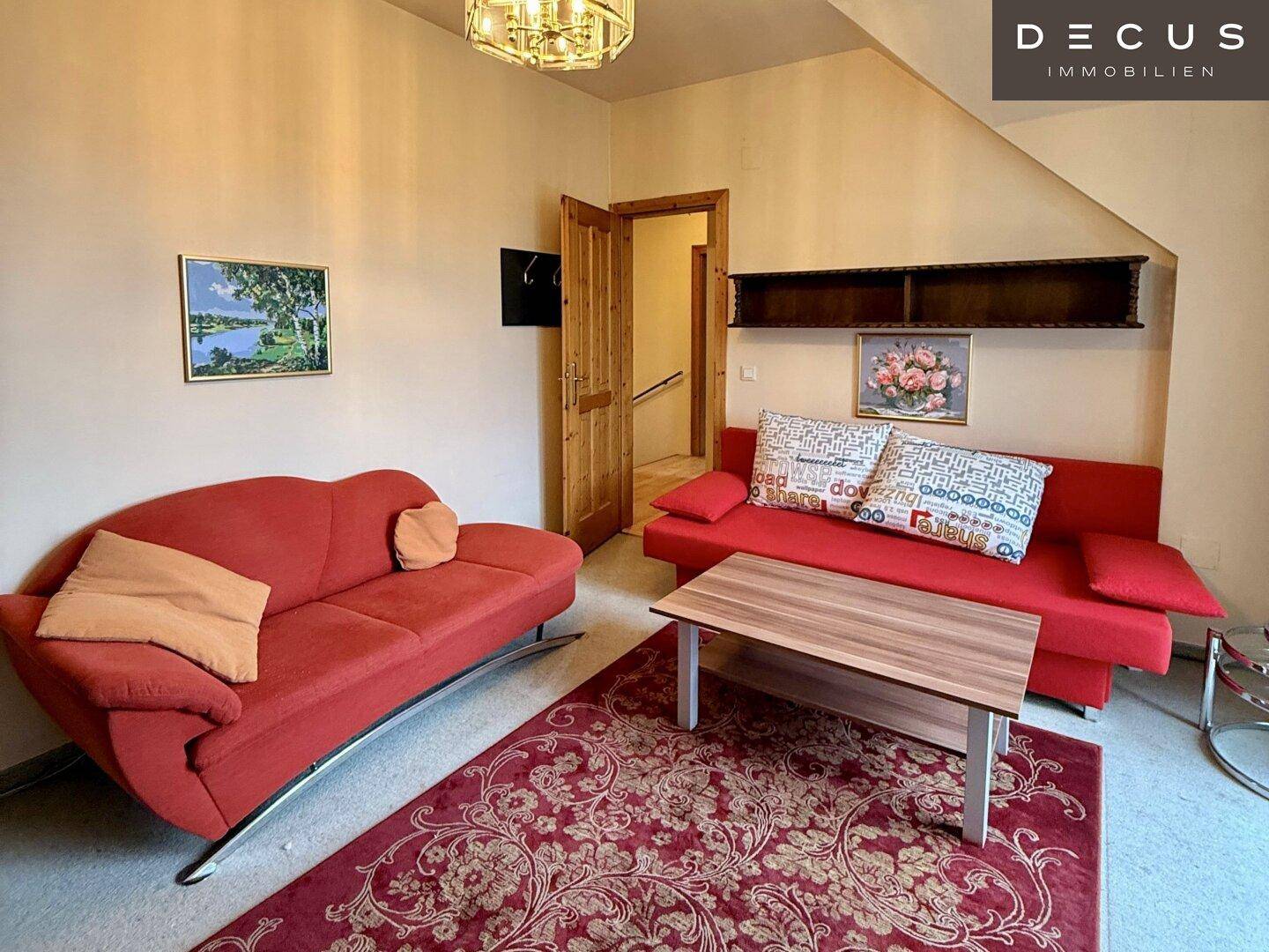 Gemütliches Schlafzimmer im Dachgeschoss mit rotem Sofa und Teppich.