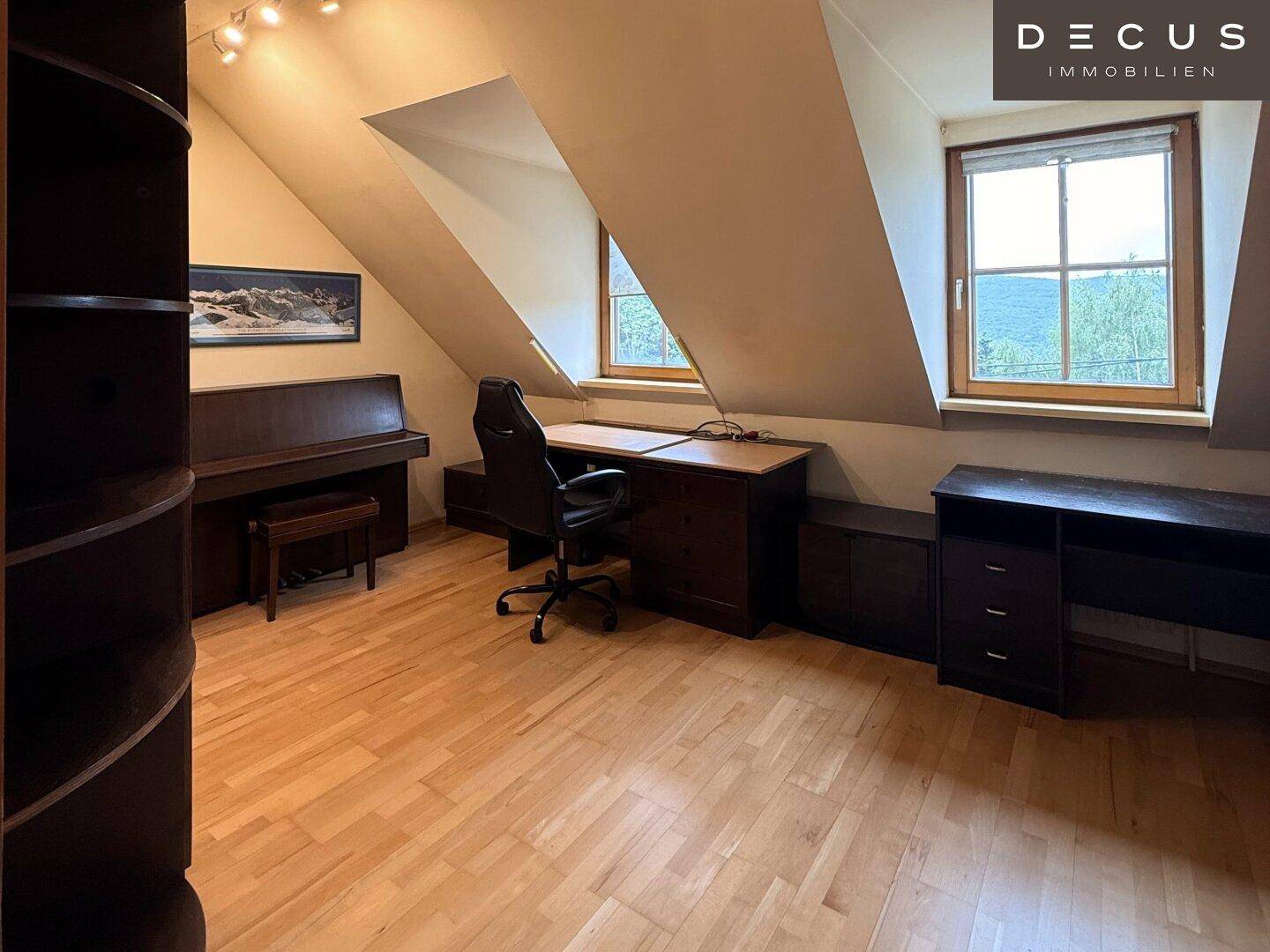 Geräumiges Arbeitszimmer im Dachgeschoss mit Holzboden, Schreibtisch und Dachschrägen.