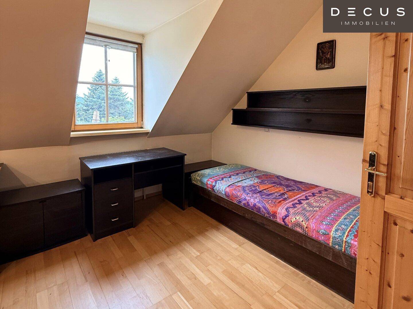 Helles Schlafzimmer im Dachgeschoss mit Holzboden, Einzelbett und Dachschräge.