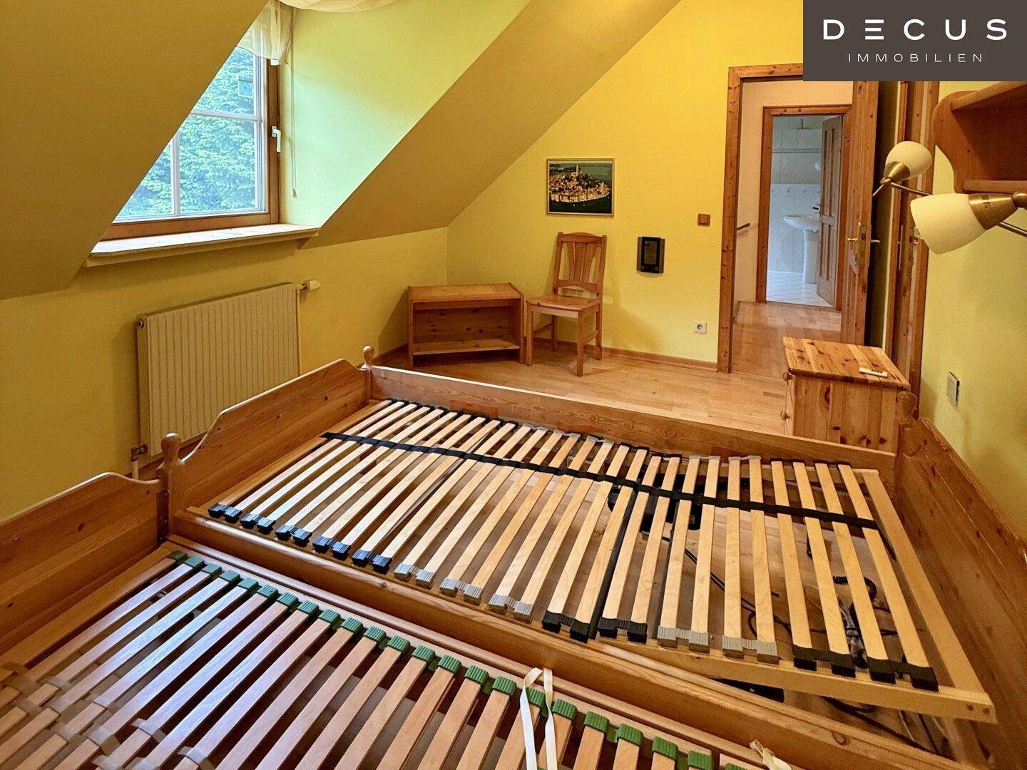 Schlafzimmer im Dachgeschoss mit gelben Wänden und zwei Bettgestellen.