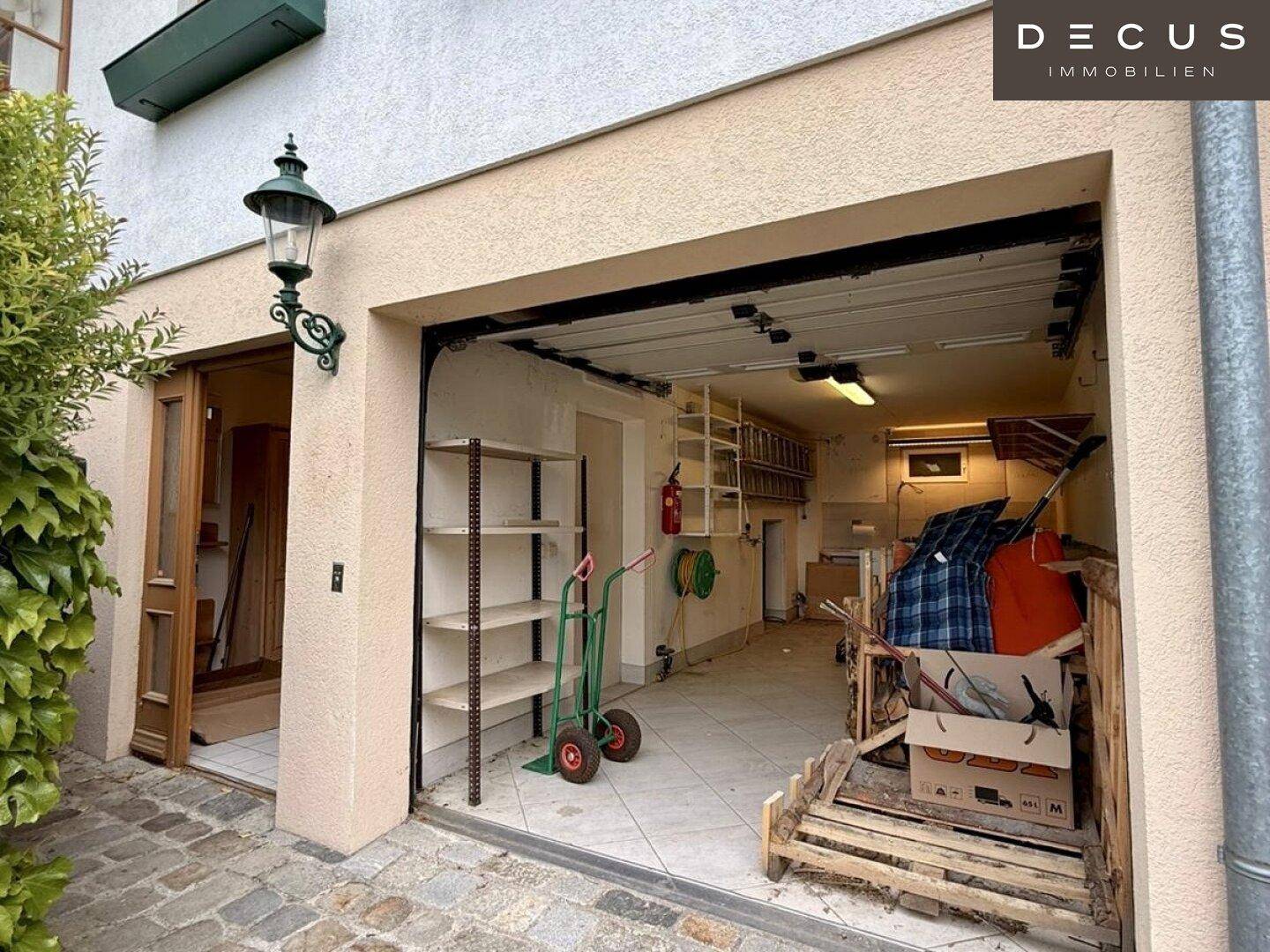 Geräumige Garage mit offenem Tor, Regalen und verschiedenen gelagerten Gegenständen.