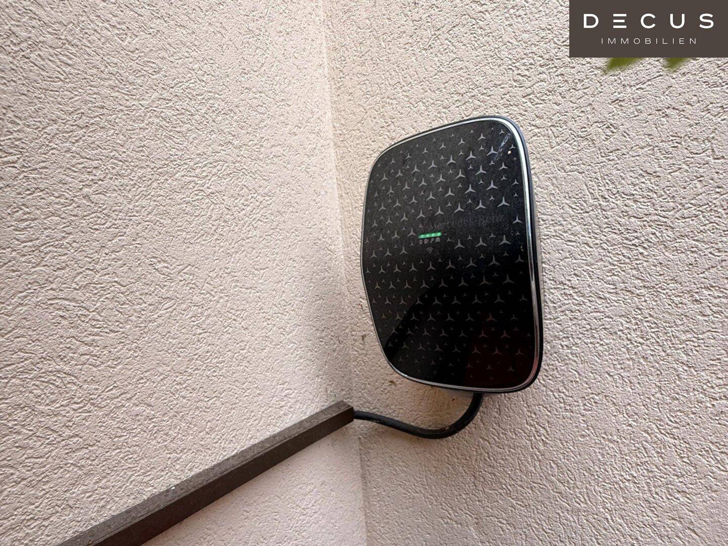 Moderne Ladestation für Elektrofahrzeuge, an einer hellen Außenwand montiert.