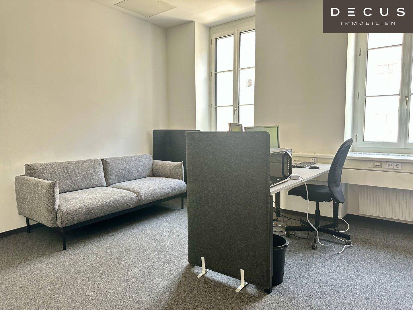 Gemütliches Büro mit einem Sofa, einem Arbeitsplatz und Trennwänden für mehr Privatsphäre.