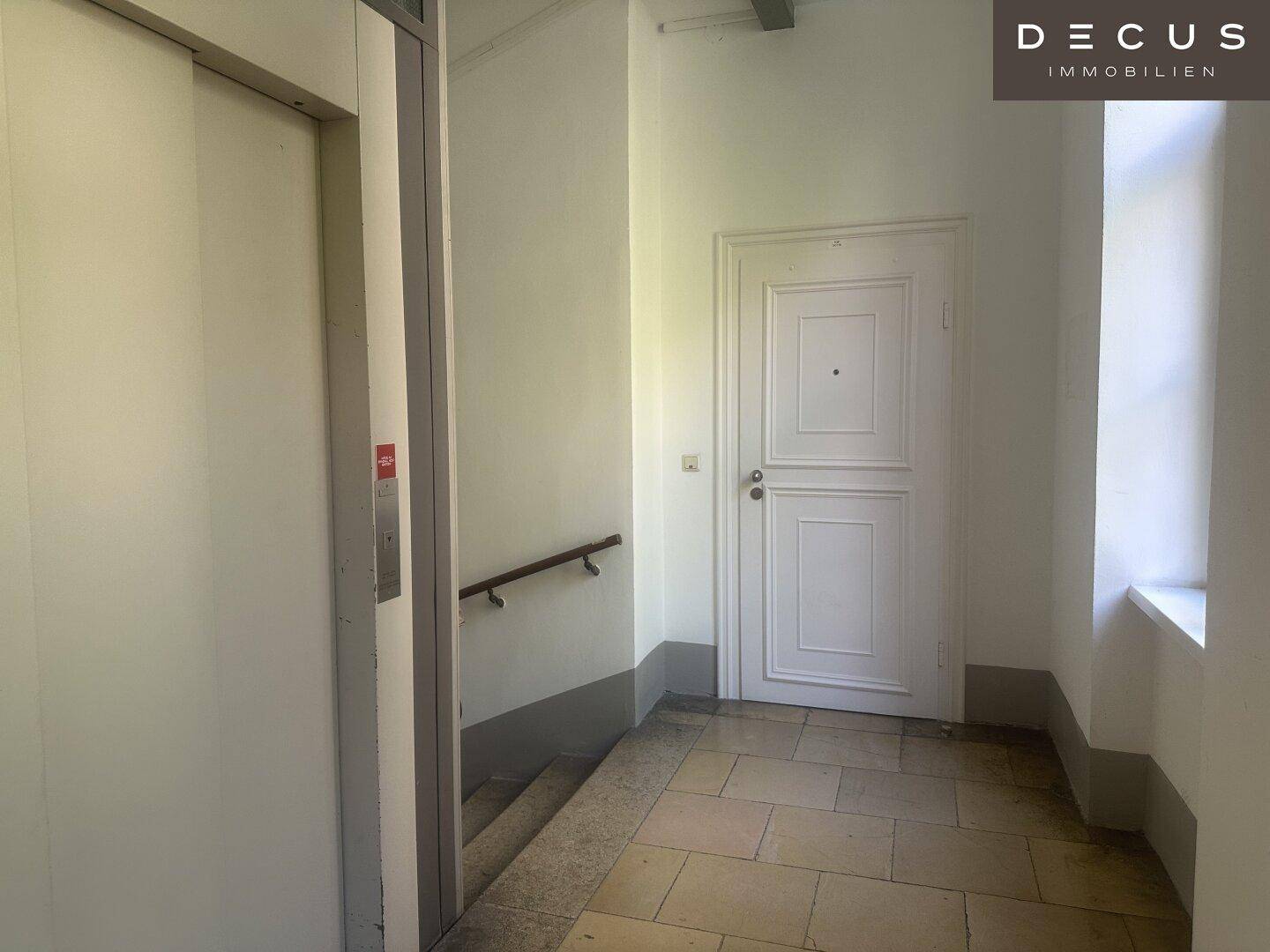 Treppenhaus und Eingangsbereich mit einer klassischen weißen Tür und einem Handlauf an der Wand.