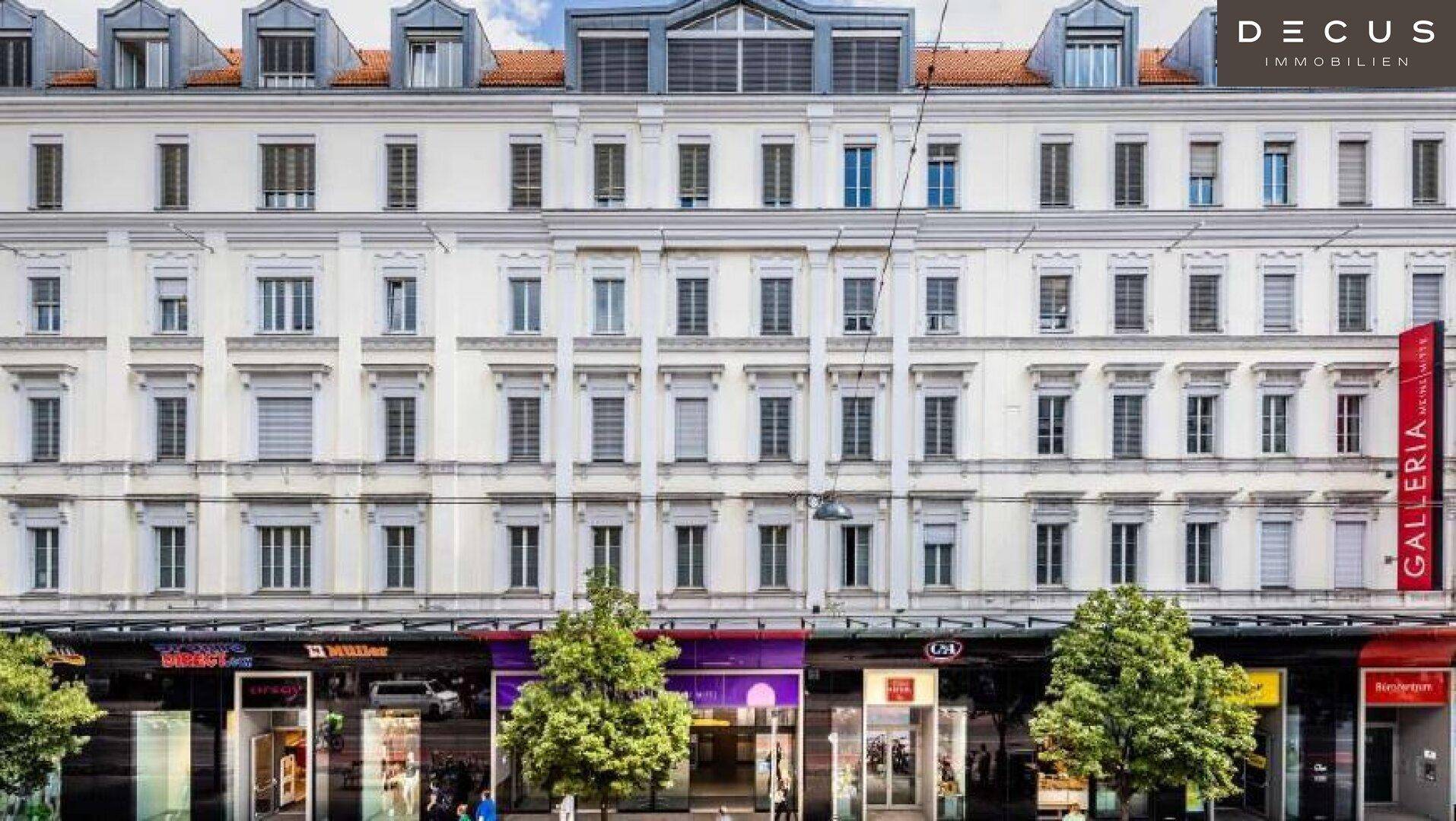 Historische Gebäudefassade mit vielen Fenstern, Geschäften im Erdgeschoss und klassischer Architektur.