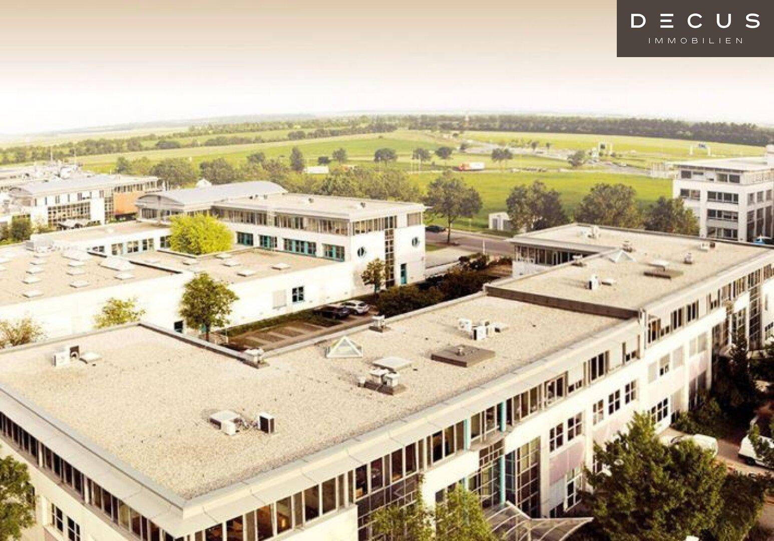 Blick von oben auf die Dächer und oberen Etagen moderner Geschäftsgebäude mit weitem Grünblick.