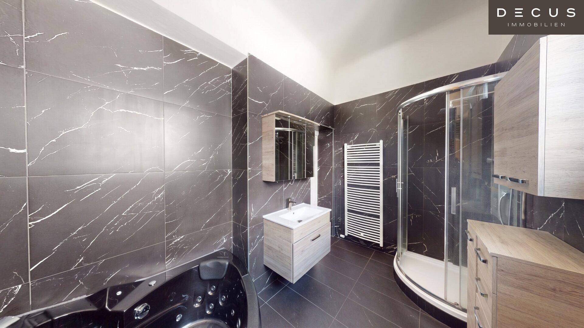 Elegantes Badezimmer mit dunklen Fliesen, Whirlpool-Badewanne und separater Duschkabine.