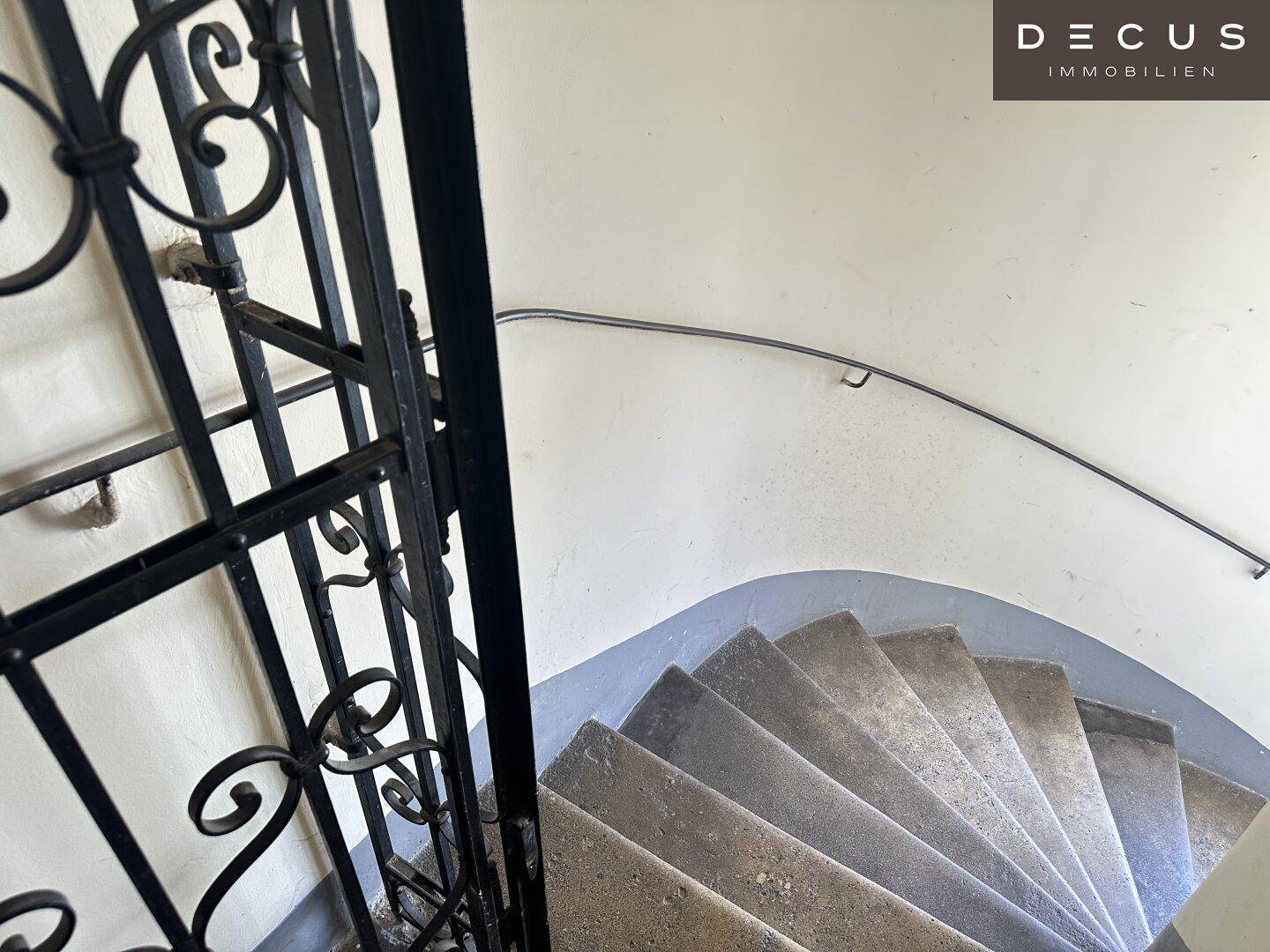 Detailansicht eines geschwungenen Treppenhauses mit schmiedeeisernem Geländer und Handlauf.