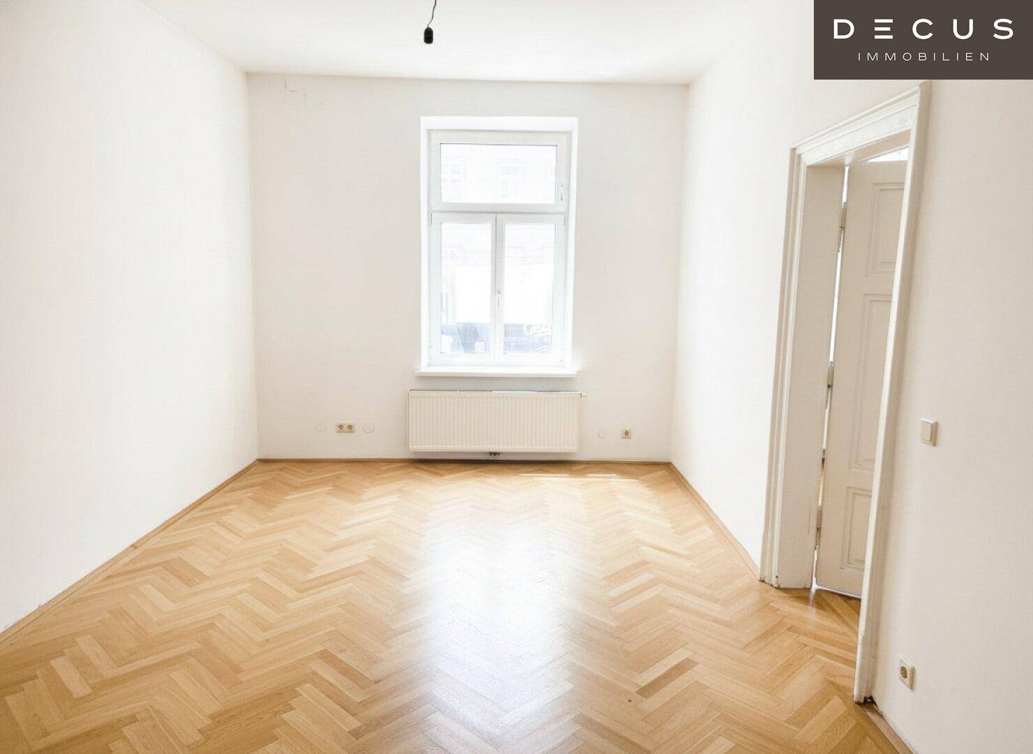 Heller Raum mit einem großen Fenster und klassischem Fischgrätparkett, ideal für Wohn- oder Schlafzimmer.