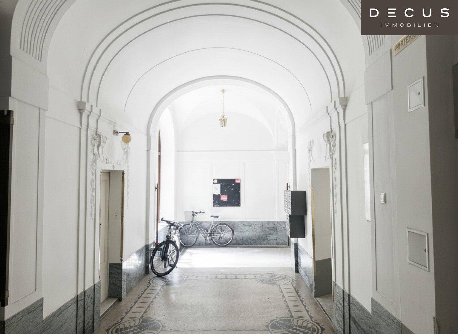 Geräumiger Eingangsbereich mit Gewölbedecken, Marmor und Fahrrädern.