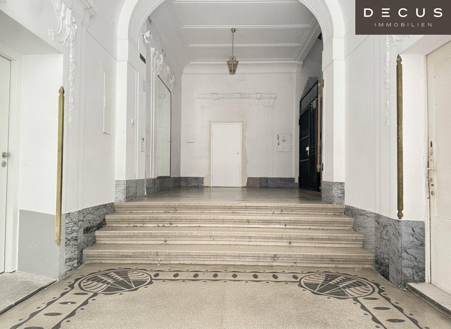 Repräsentativer Eingangsbereich mit breiter Treppe, Marmor und hohen Decken.