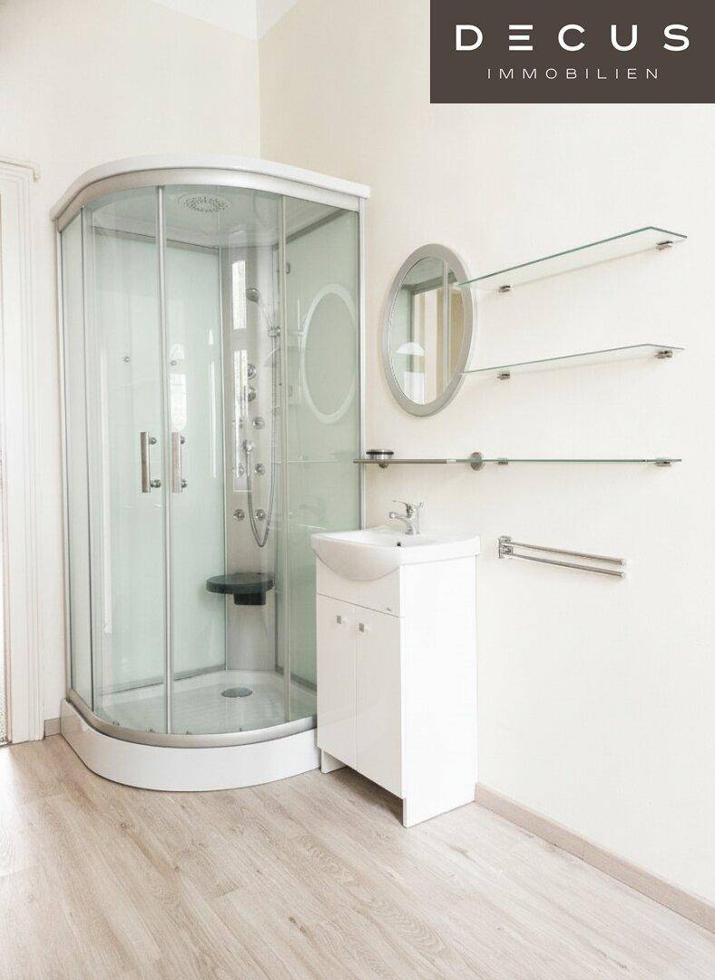 Badezimmer mit moderner Duschkabine, Waschbeckenunterschrank und hellem Holzoptik-Boden.
