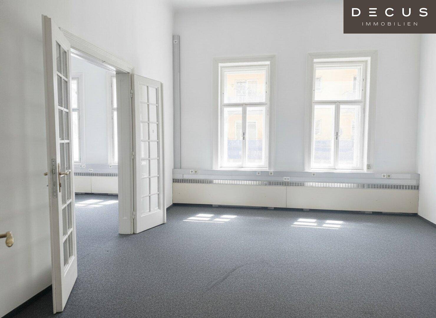 Heller Raum mit grauem Teppichboden, großen Fenstern und viel Tageslicht, ideal für Büronutzung.