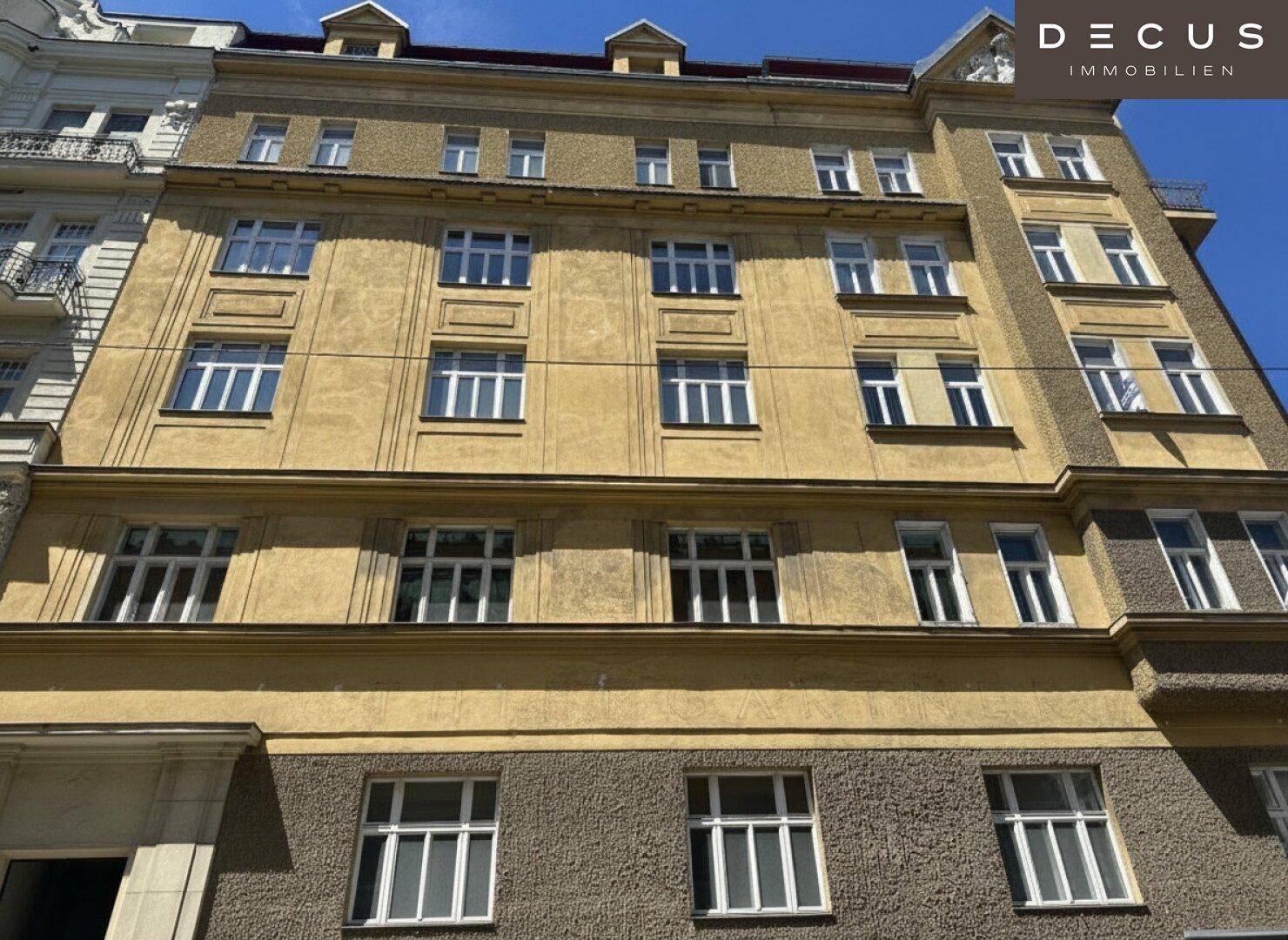 Historische Fassade eines Mehrfamilienhauses mit vielen Fenstern und klassischer Architektur.