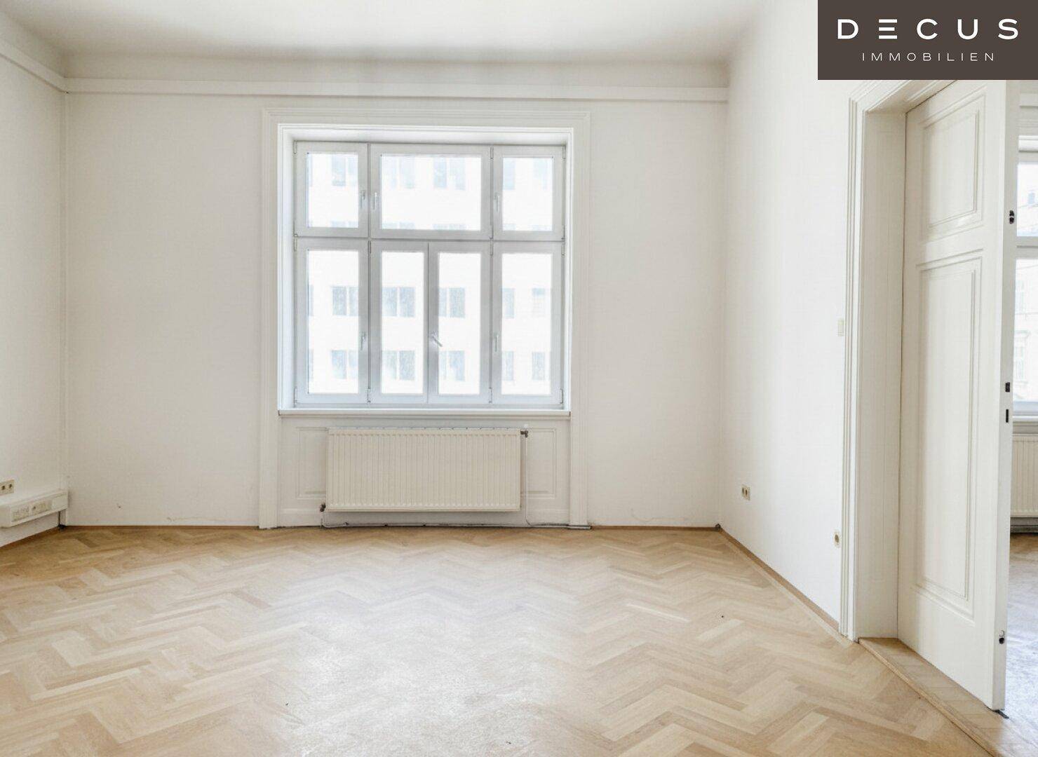 Geräumiger Raum mit großen Fenstern, die viel Licht spenden, und klassischem Fischgrätparkett.