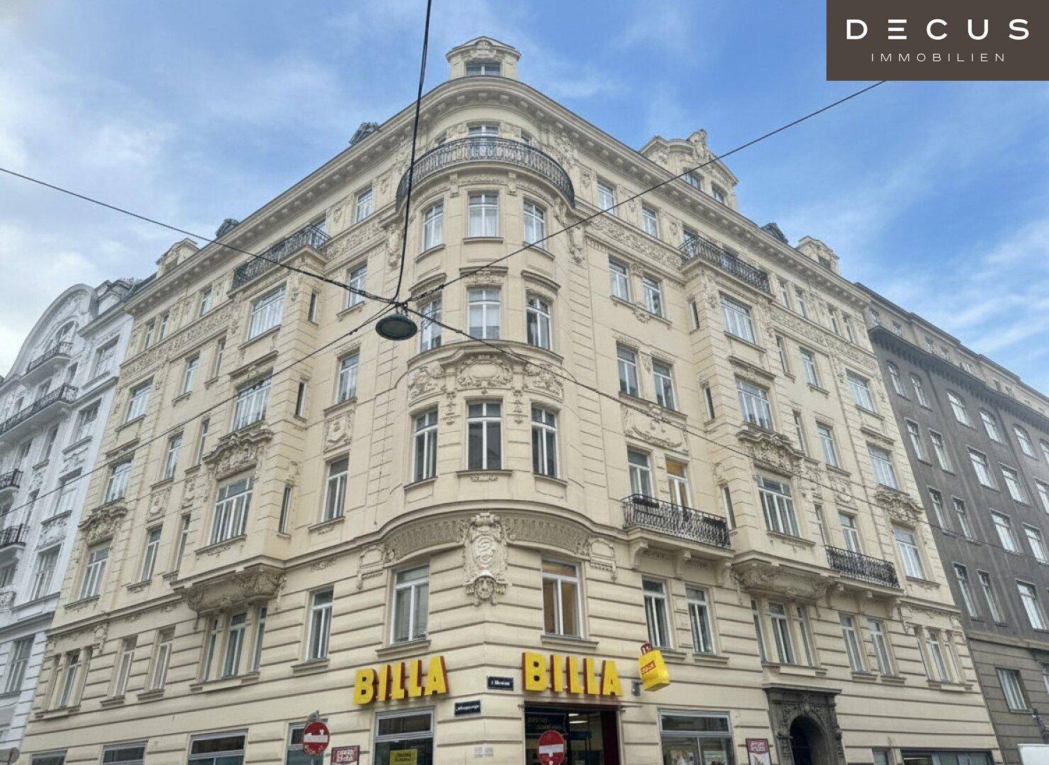 Historisches Eckgebäude mit reich verzierten Fassaden, vielen Fenstern und Balkonen in der Stadt.