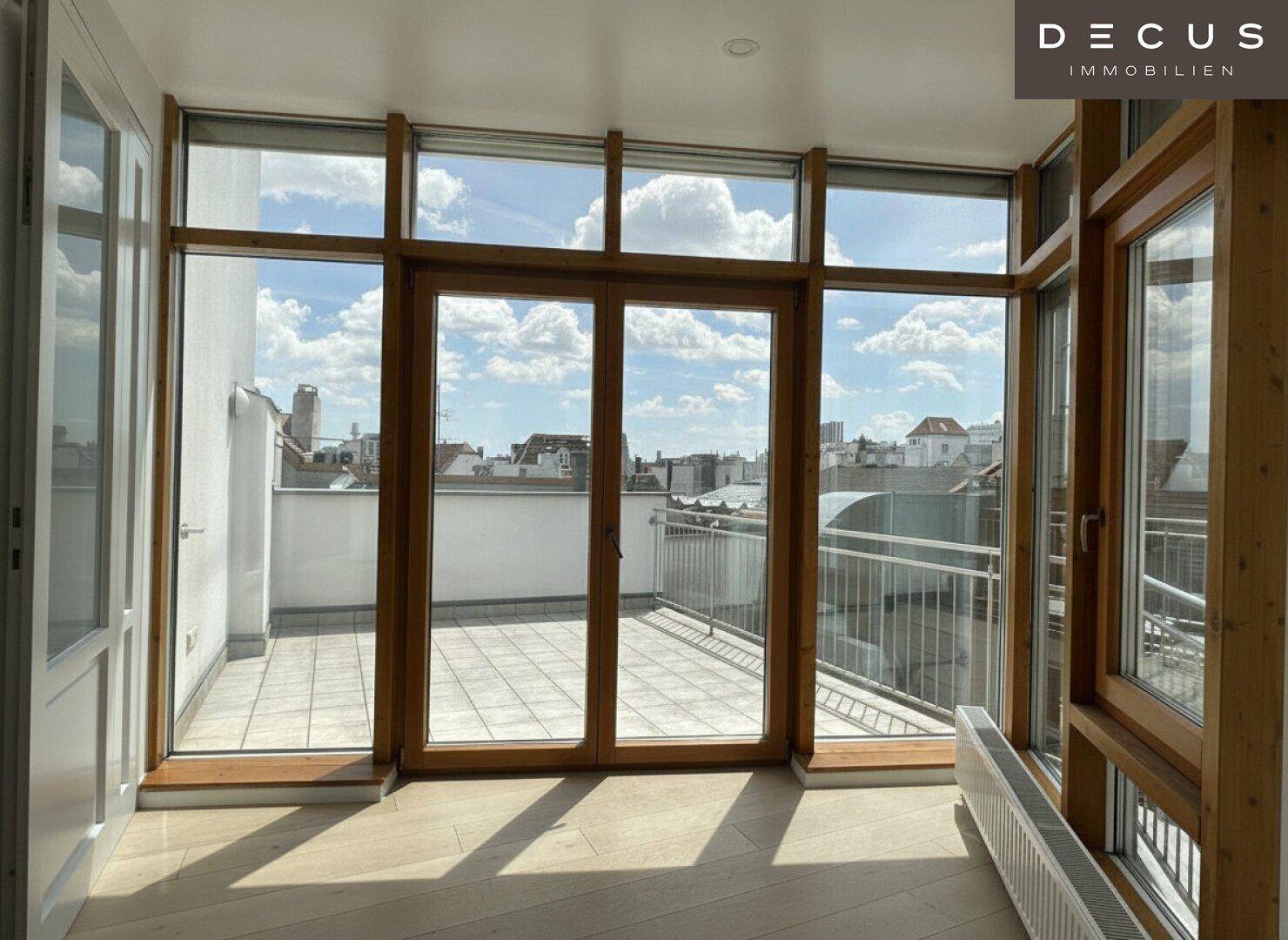 Heller Wohnbereich mit großen Fenstern und Zugang zu einer Terrasse mit Stadtblick.