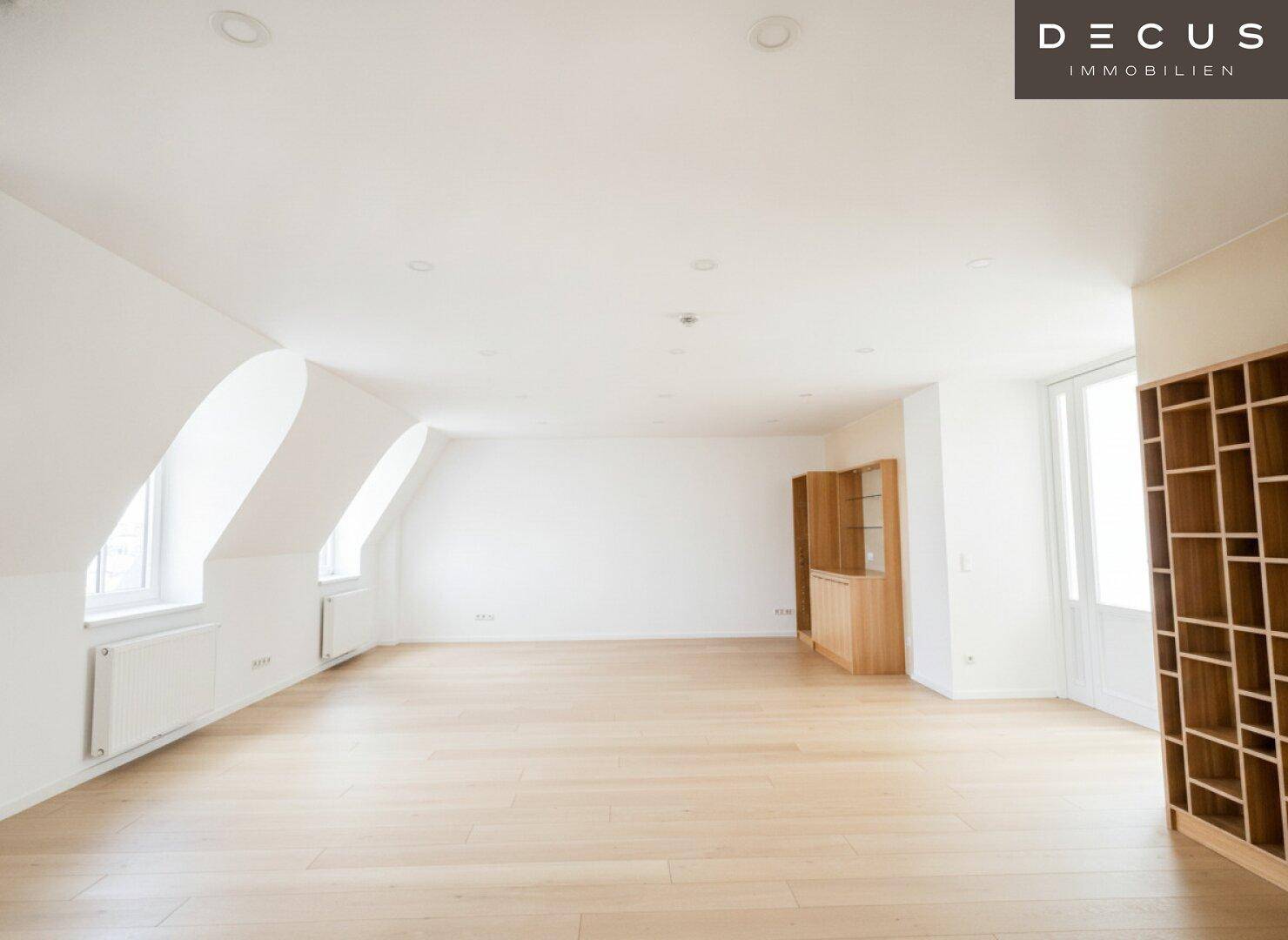 Geräumiger Wohnbereich mit Holzboden, Dachschrägen und einem dekorativen Bücherregal.