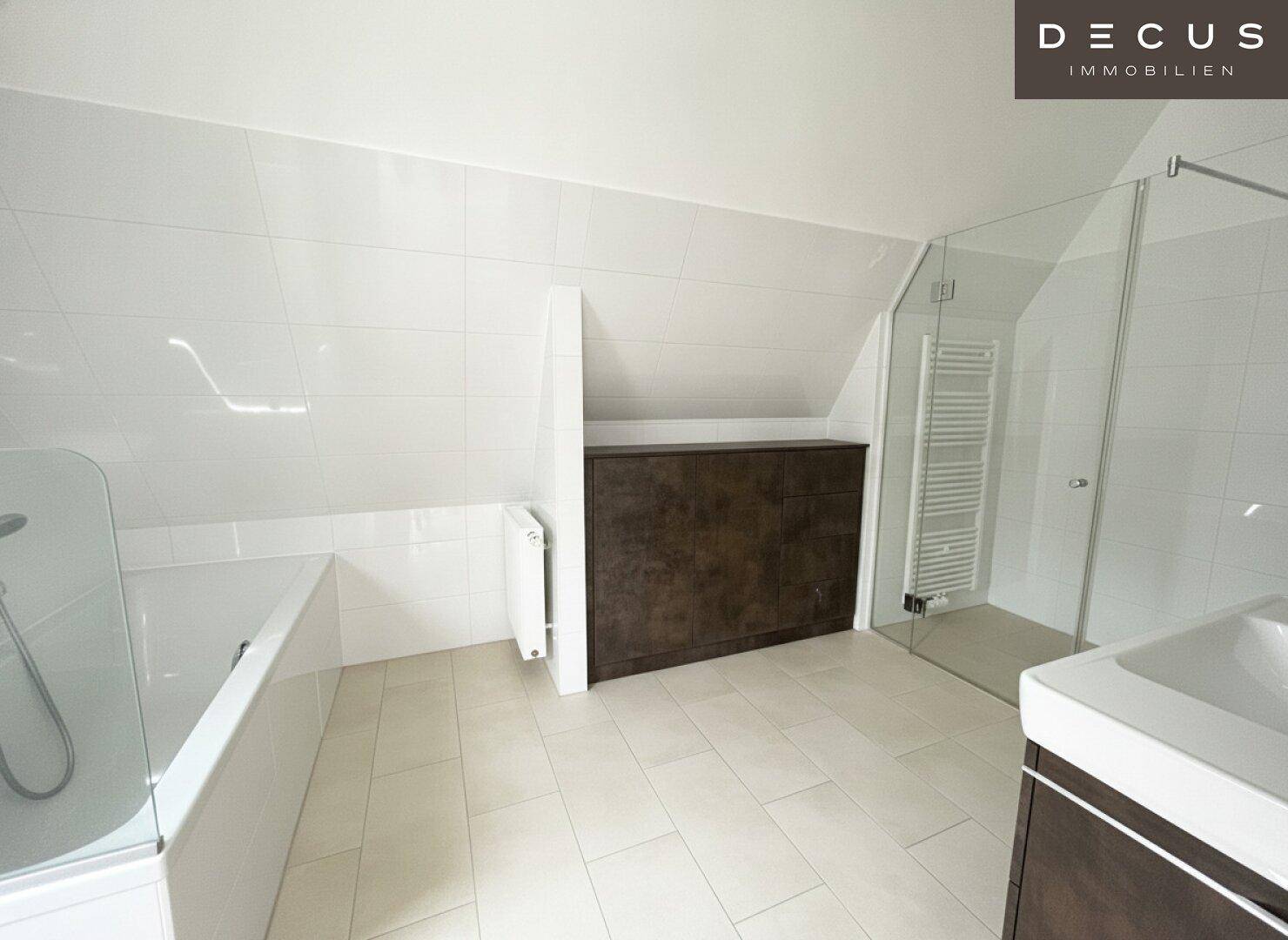 Modernes Badezimmer mit Fliesenboden, Badewanne und einer begehbaren Dusche unter der Dachschräge.