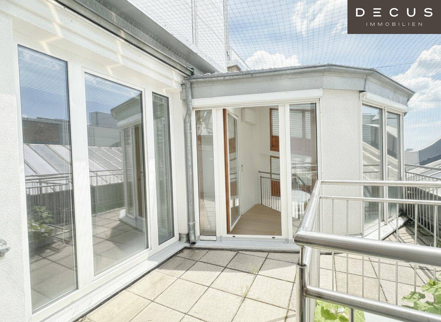 Dachterrasse mit Fliesenboden und Glasfront, die den Zugang zu den Innenräumen ermöglicht.