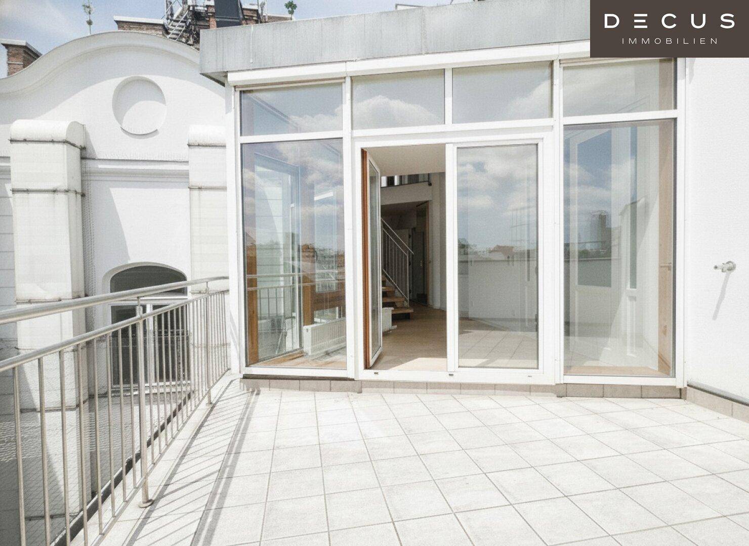 Große Dachterrasse mit Fliesenboden und Glasfront, die den Zugang zum Innenbereich ermöglicht.