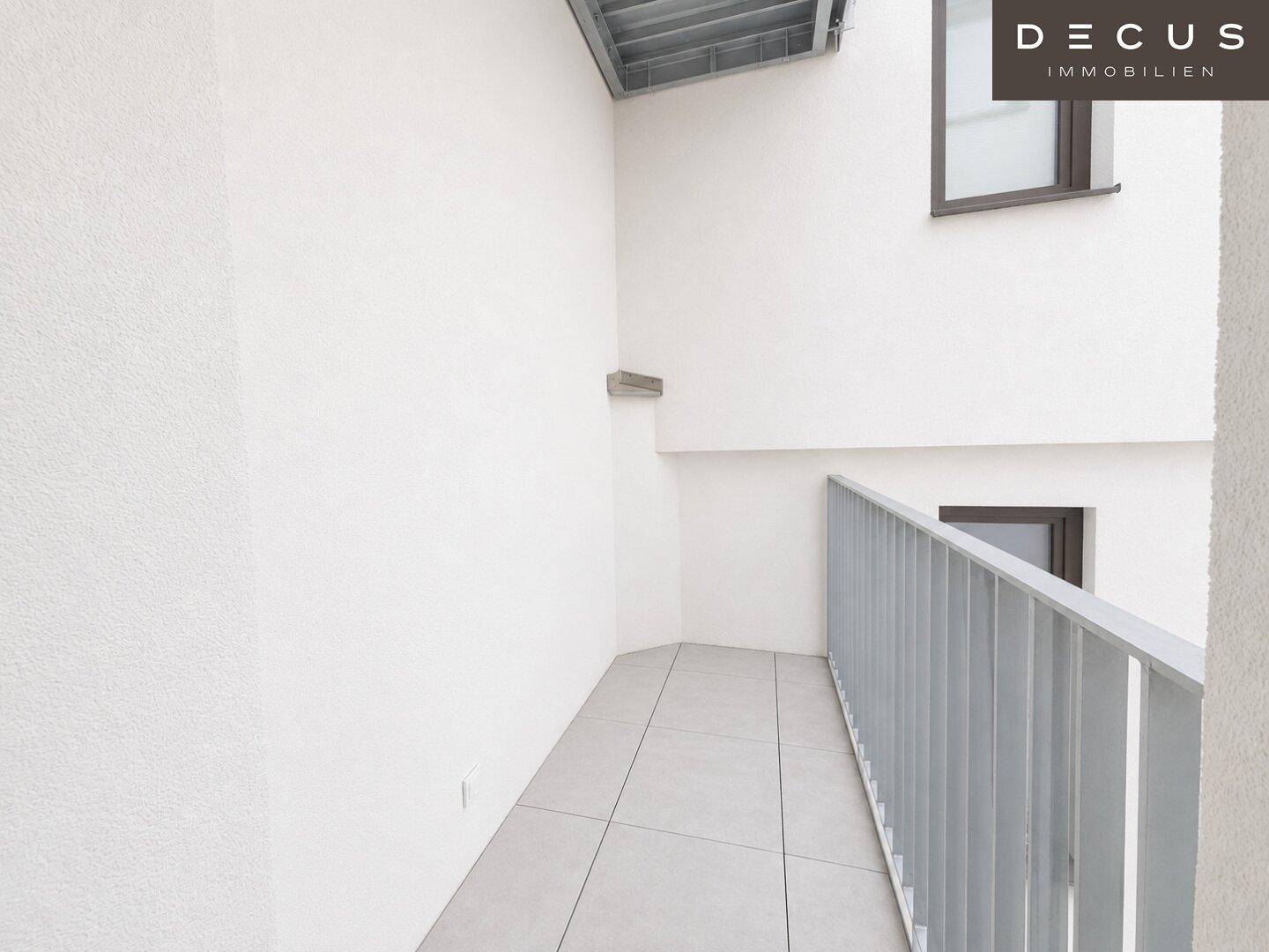 Leerer Balkon mit Fliesenboden und modernem Metallgeländer.