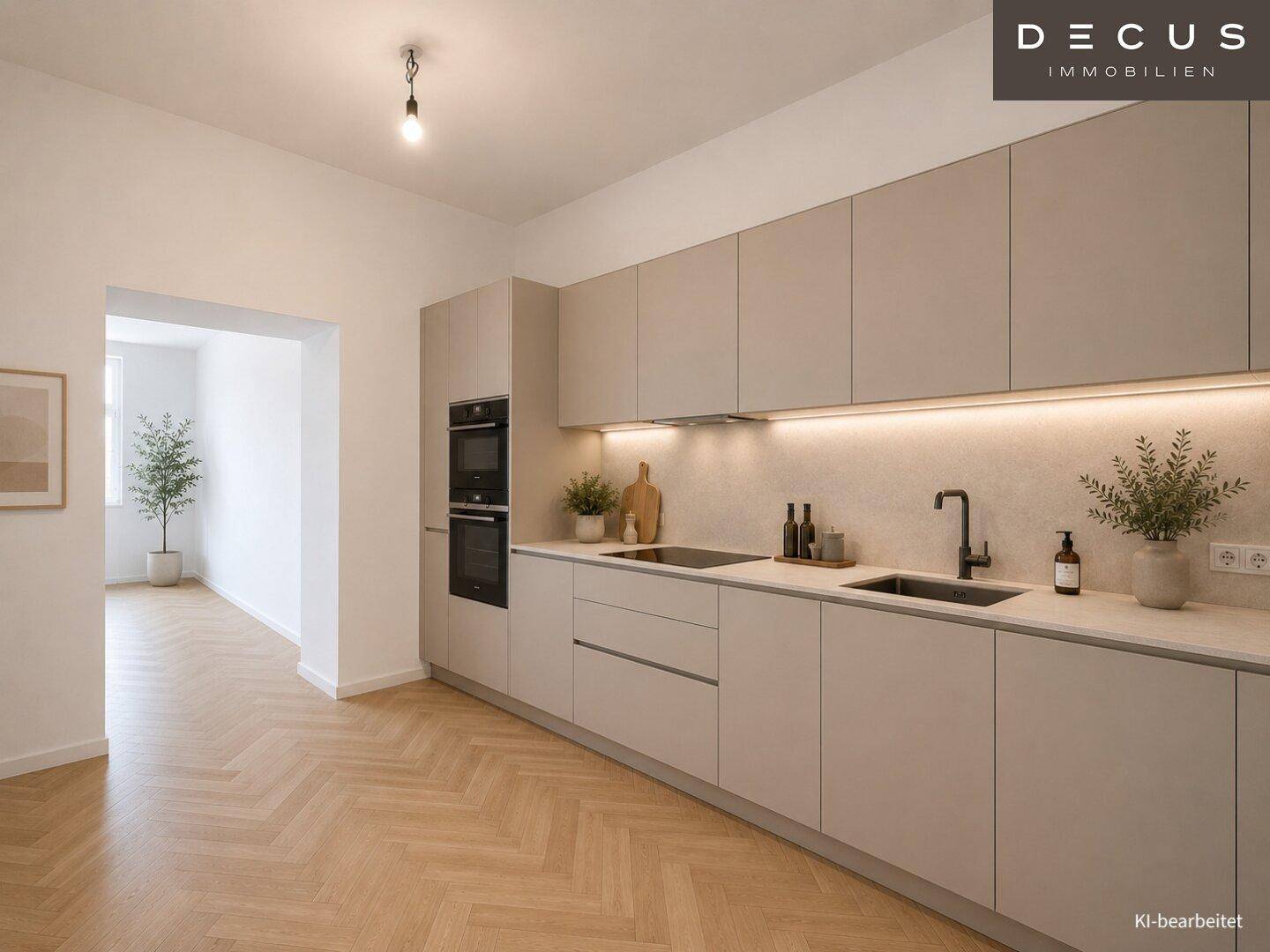 Moderne Einbauküche mit beigen Schränken, integrierten Geräten und Fischgrätparkett.