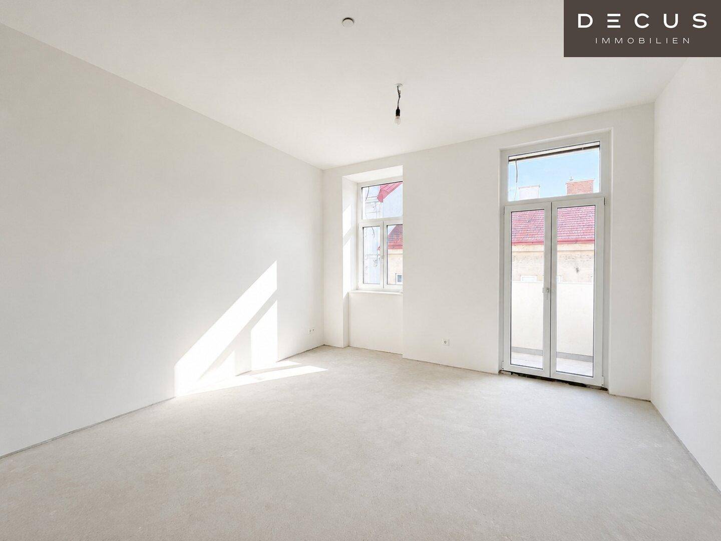 Unmöblierter, heller Raum mit weiß gestrichenen Wänden und Zugang zu einem Balkon.