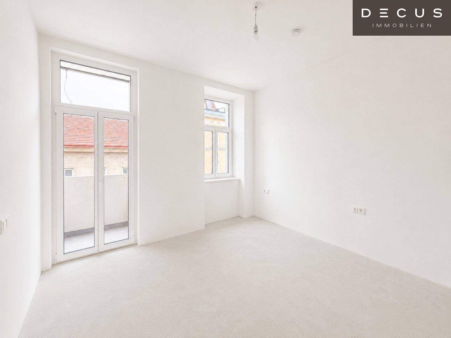 Unmöbliertes Schlafzimmer mit hellen Wänden, Holzboden und Zugang zu einem Balkon.