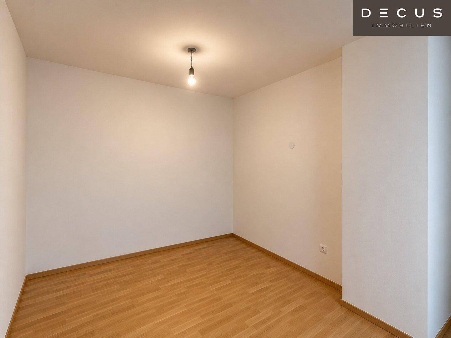 Leeres Schlafzimmer mit hellem Holzboden und weißen Wänden, bereit zur individuellen Gestaltung.