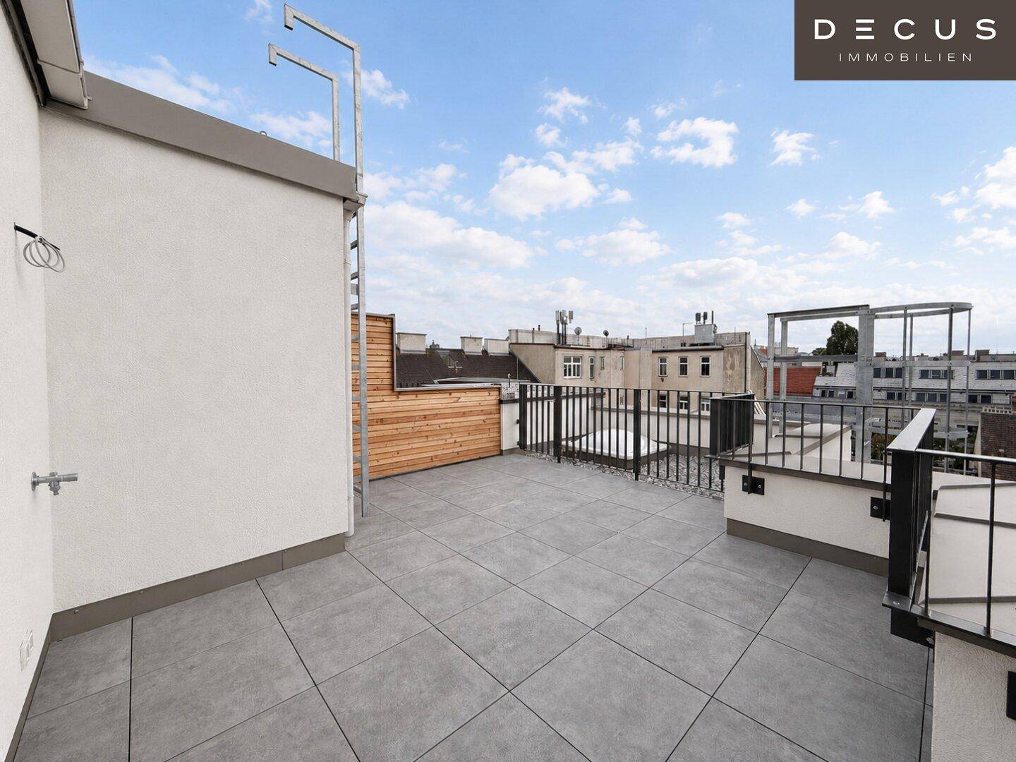 Geräumige Dachterrasse mit Fliesenboden und Blick über die Stadt.