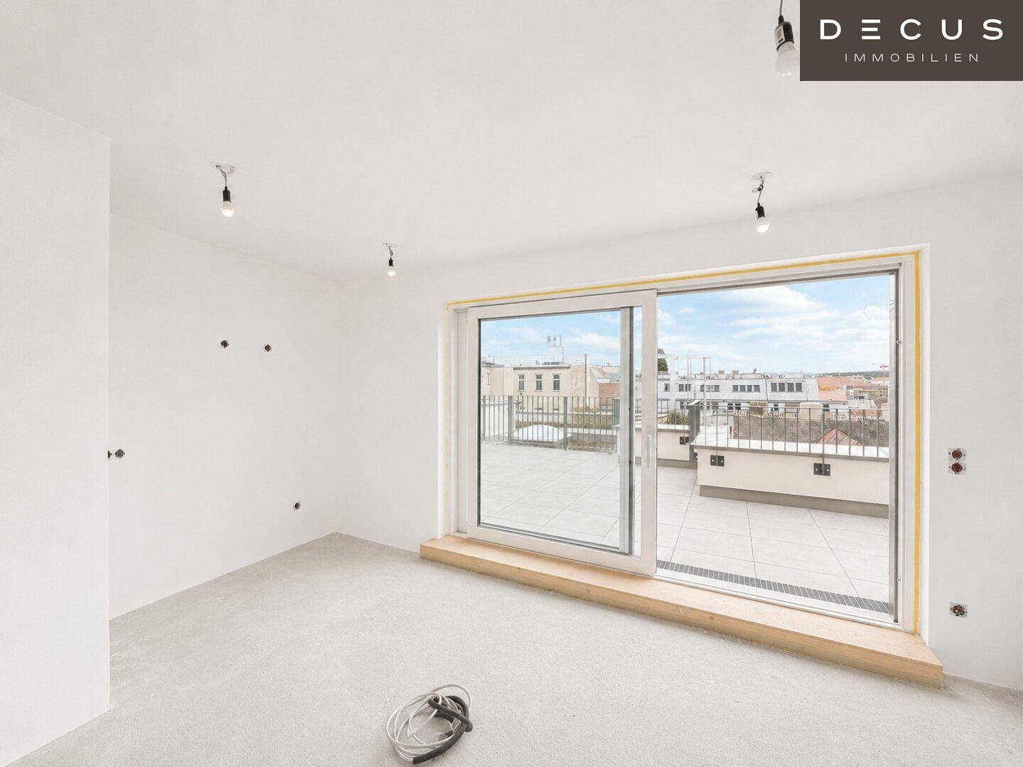 Unfertiger Raum mit großen Schiebetüren, die auf eine Terrasse führen, bereit für den Ausbau.