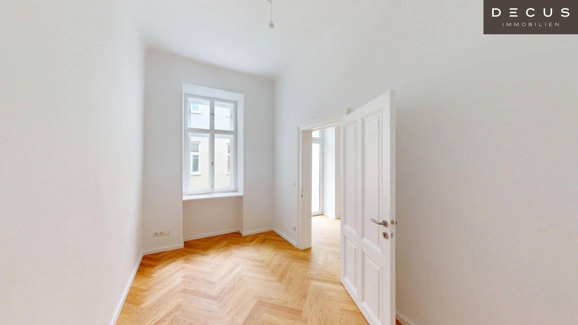 Ruhiges, helles Zimmer mit Fischgrätparkett und einem hohen Fenster, ideal als Schlaf- oder Arbeitszimmer.