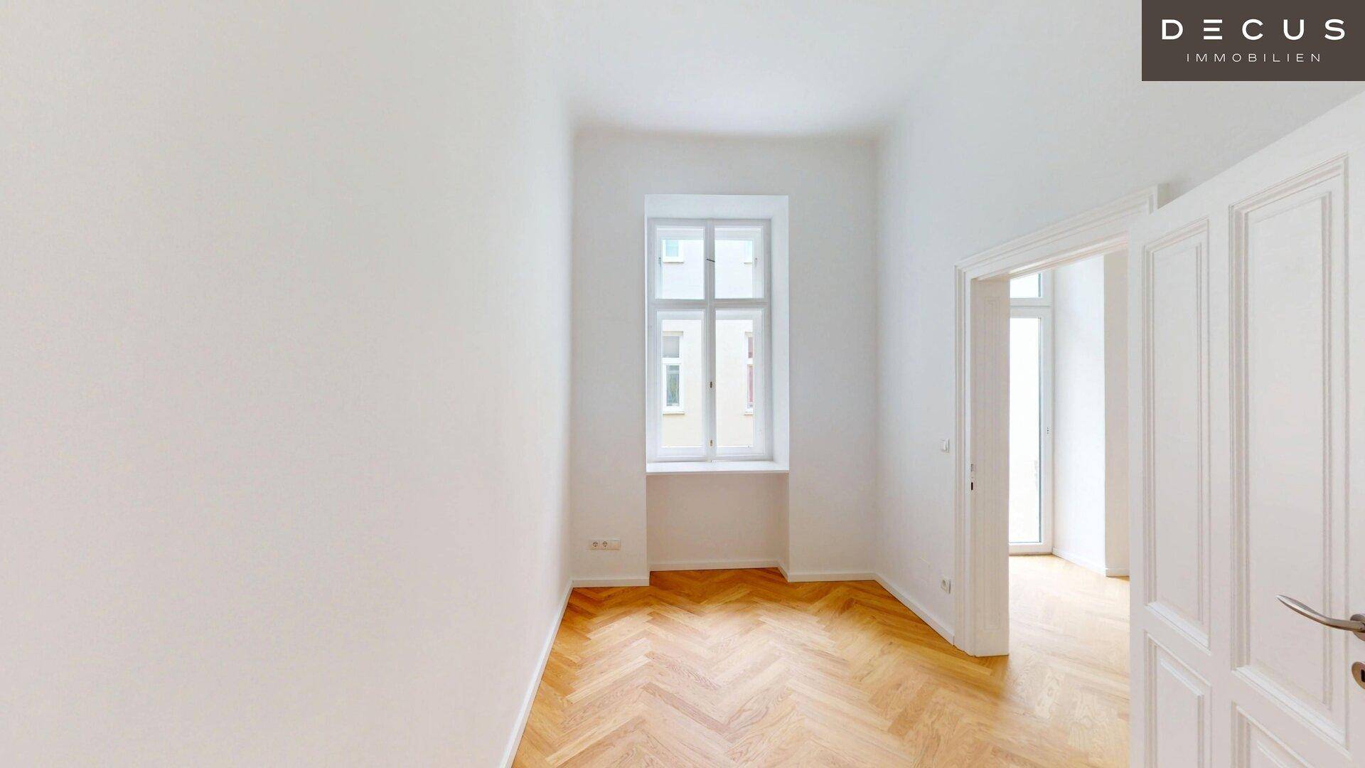 Schmaler, heller Raum mit Fischgrätparkett und einem hohen Fenster, das eine angenehme Atmosphäre schafft.