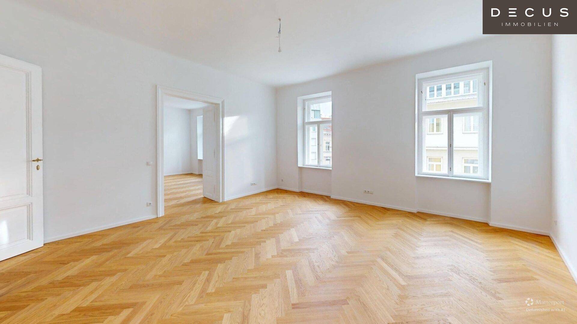 Geräumiges, helles Zimmer mit klassischem Fischgrätparkett und zwei hohen Fenstern, ideal für Wohnzwecke.
