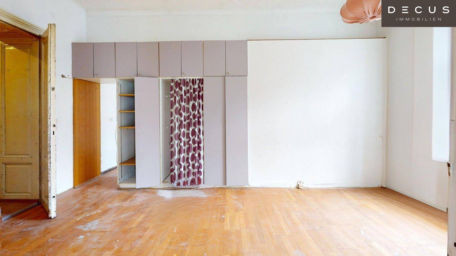 Geräumiges Schlafzimmer mit Parkettboden und Einbauschränken mit Vorhang.