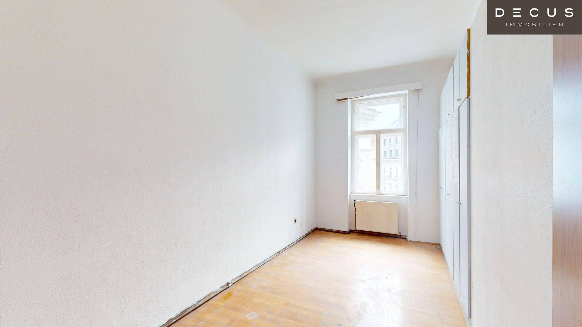Helles Schlafzimmer mit Parkettboden, Fenster und Einbauschränken.