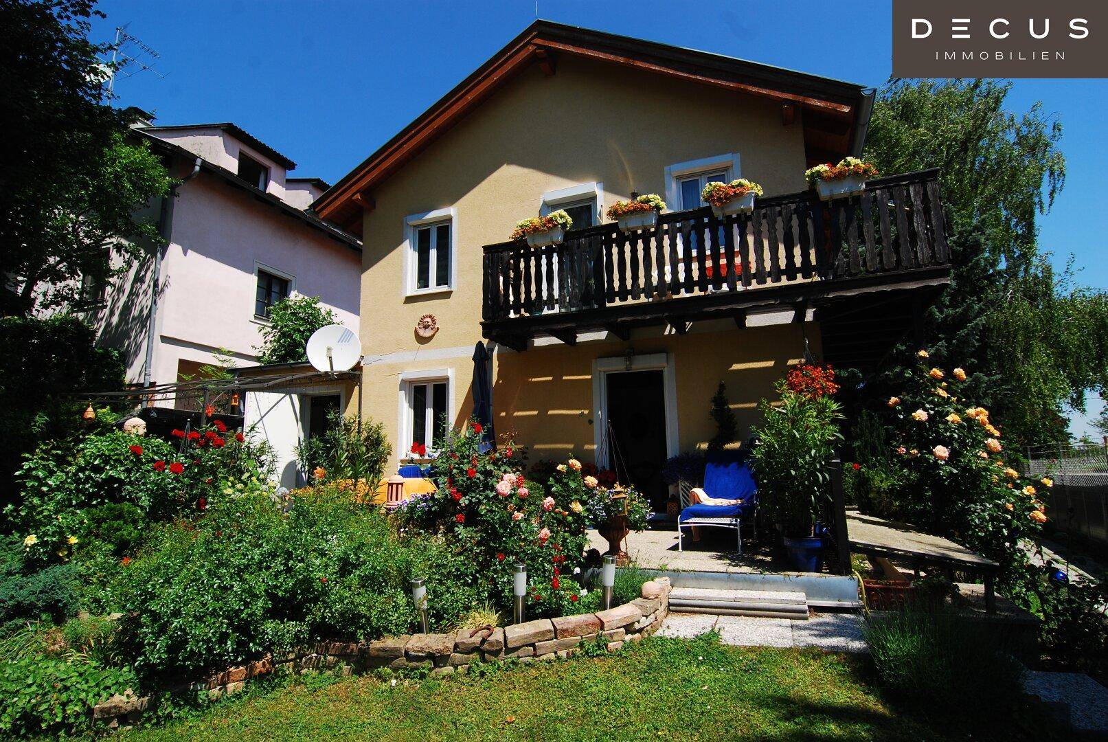 Ansicht des Hauses mit Balkon, Blumenkästen und einem liebevoll gestalteten Gartenbereich.