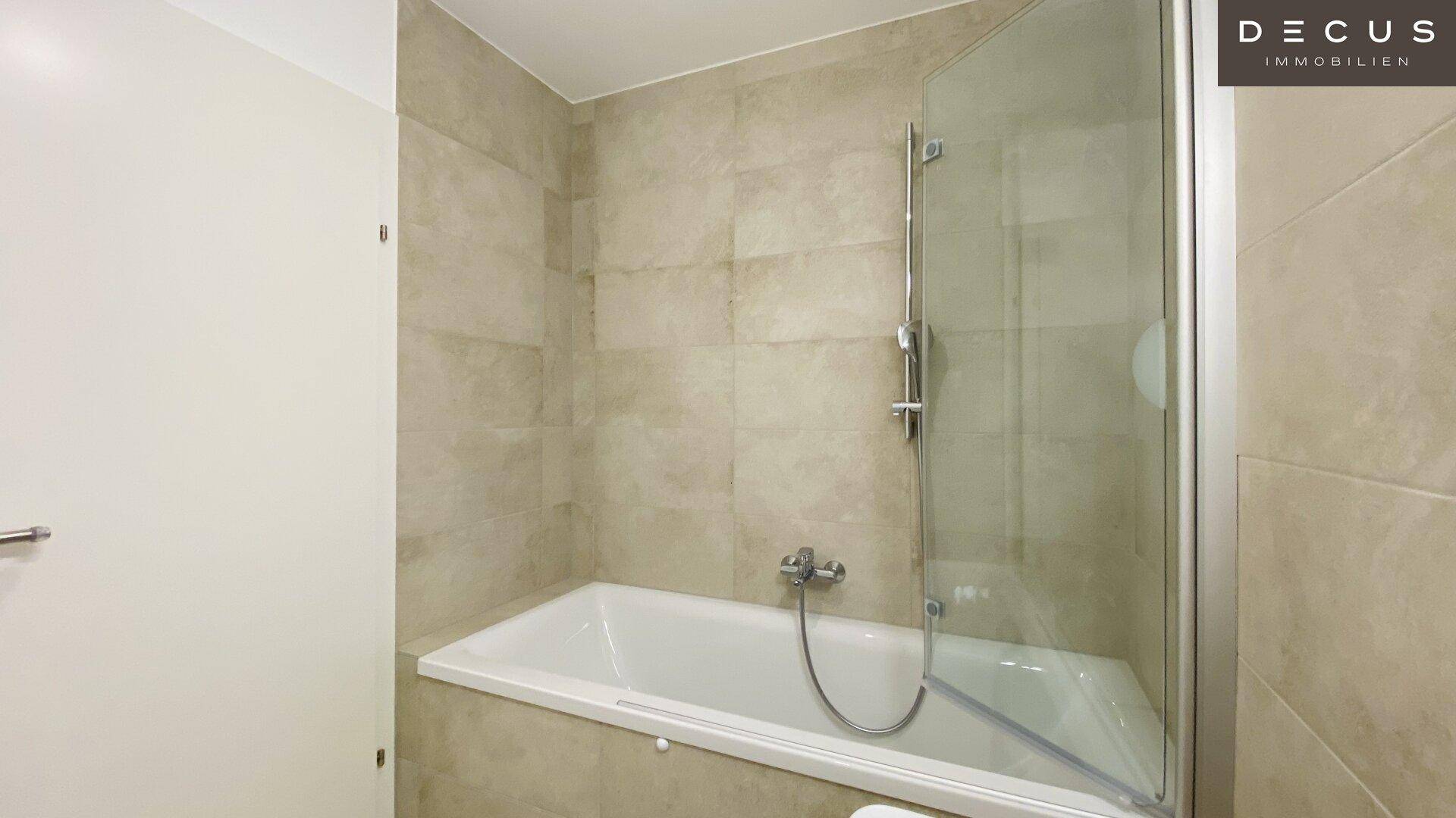 Modernes Badezimmer mit Badewanne, Duschabtrennung und beigefarbenen Fliesen.