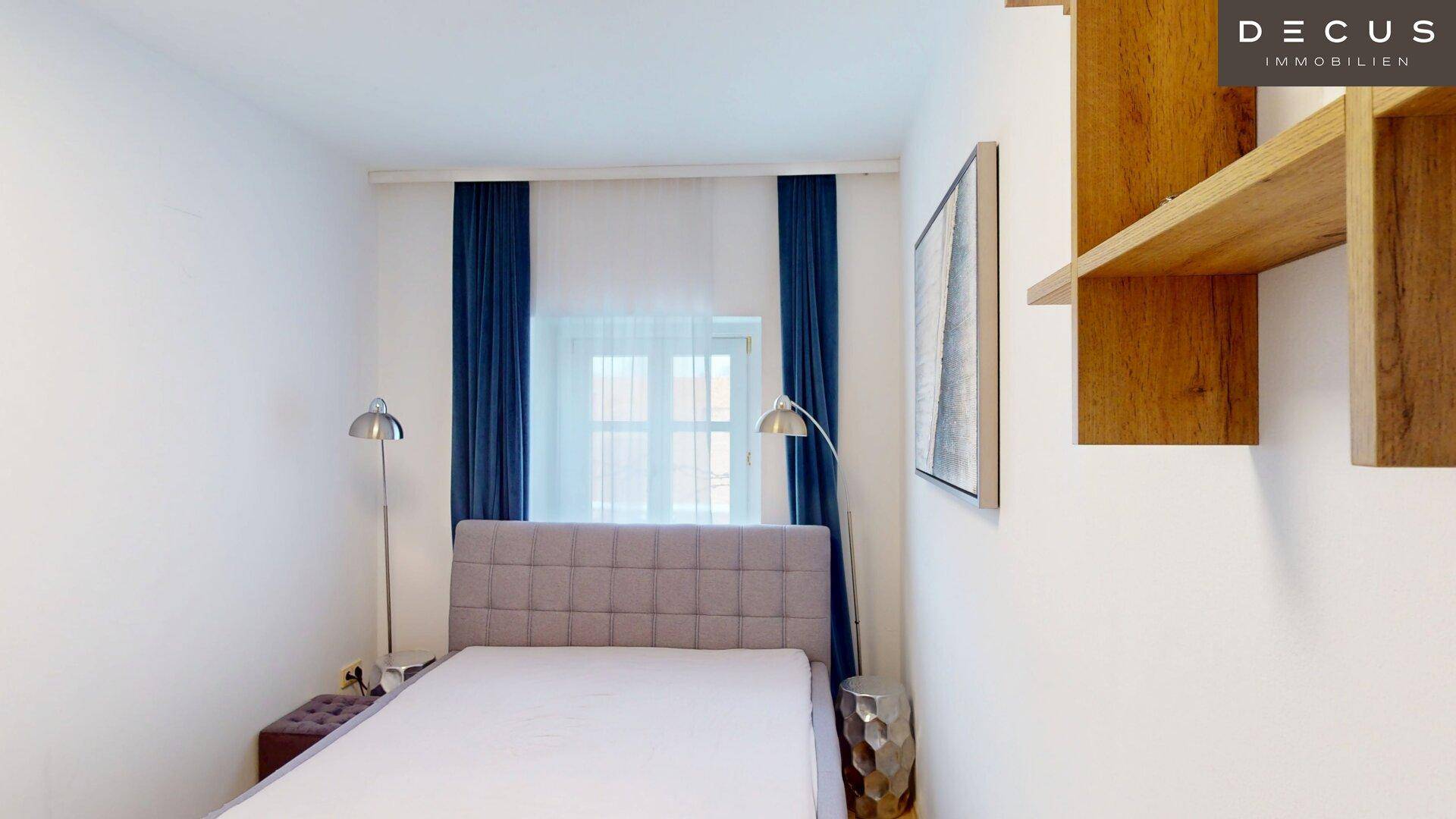 Helles Schlafzimmer mit modernem Bett, blauen Vorhängen und Holzregalen.