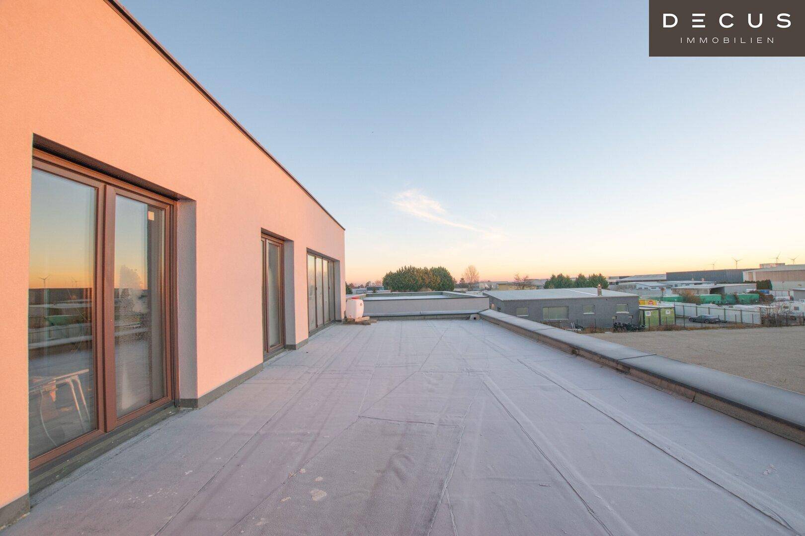 Große Dachterrasse mit weitem Blick über die Umgebung bei Sonnenuntergang.