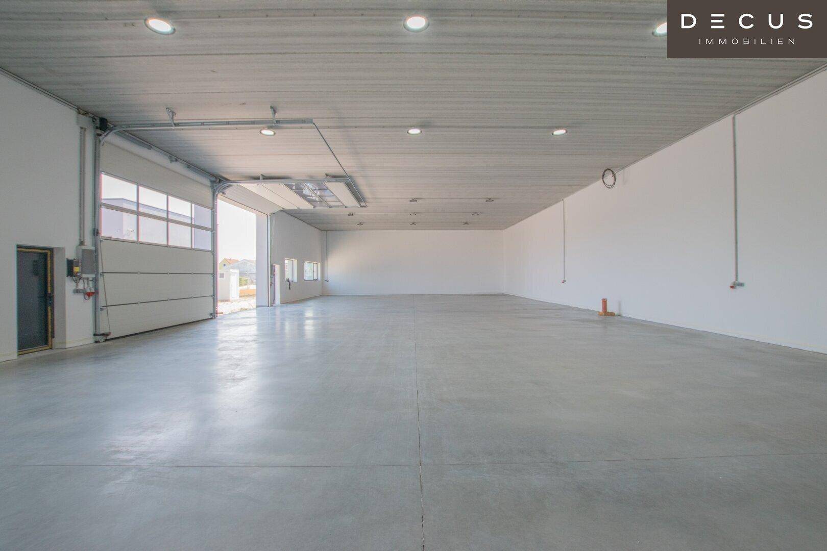 Helle Lagerhalle mit offenem Rolltor und glattem Betonboden.